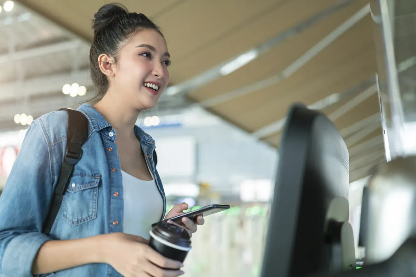 Woman in airport smiling while holding cellphone