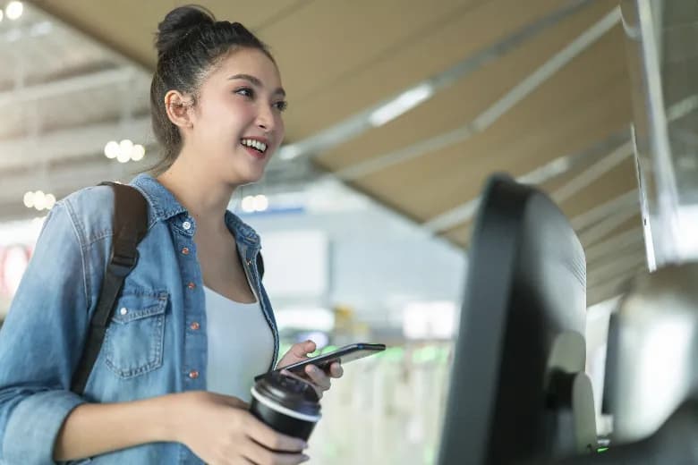 Woman in airport smiling while holding cellphone